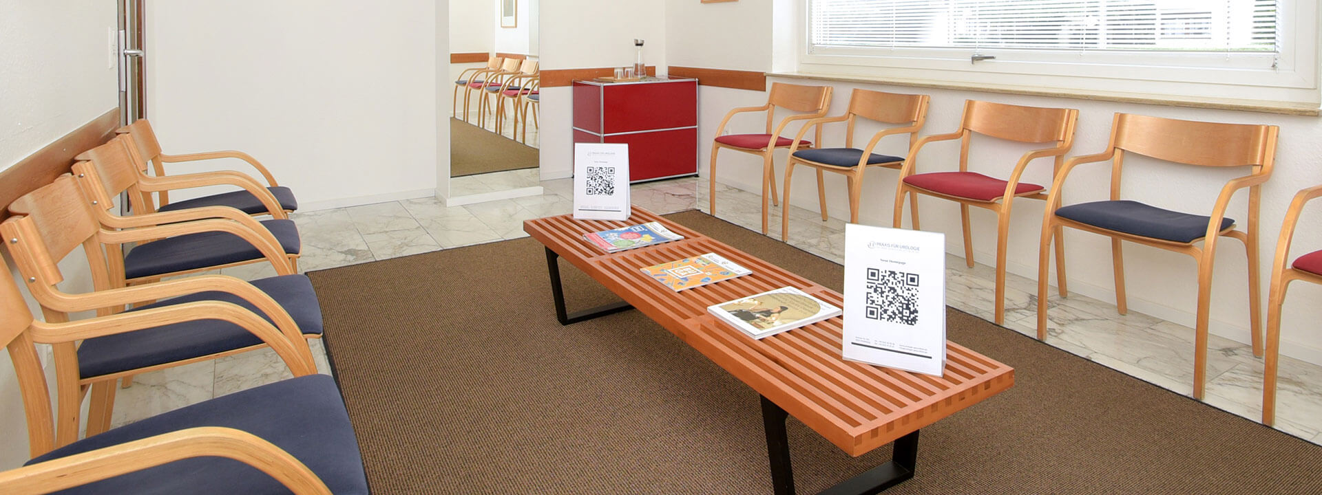 Blick in das Wartezimmer der Praxis mit Stühlen, Tisch und Informationsmaterial zum lesen